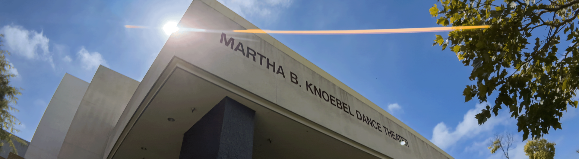 Martha B. Knoebel Dance Theater front with a lens flare against a blue sky