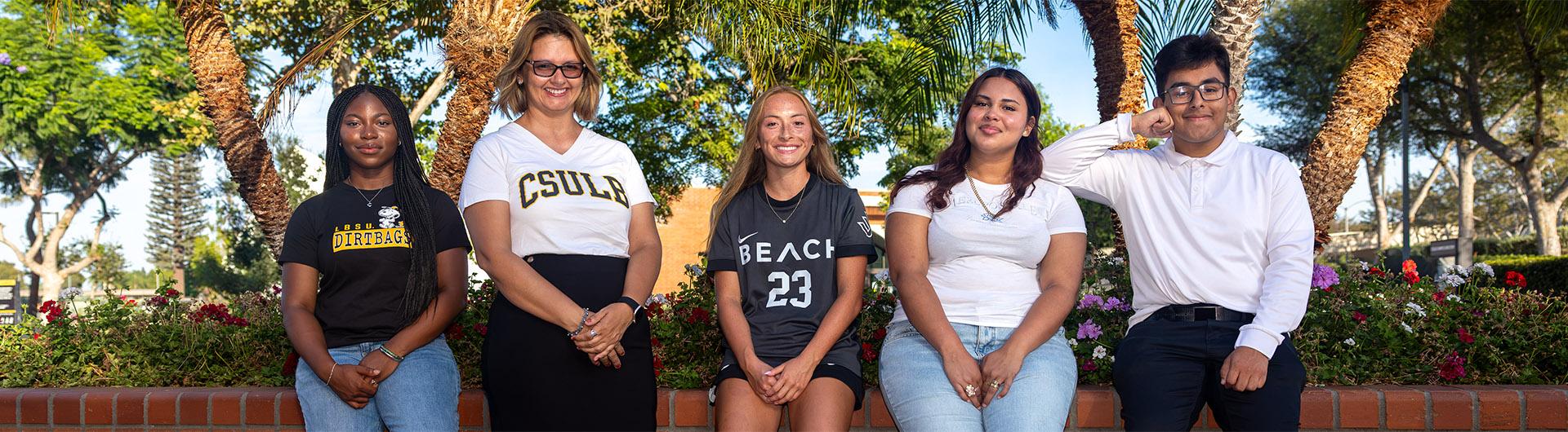 Five people pose for a photo on campus