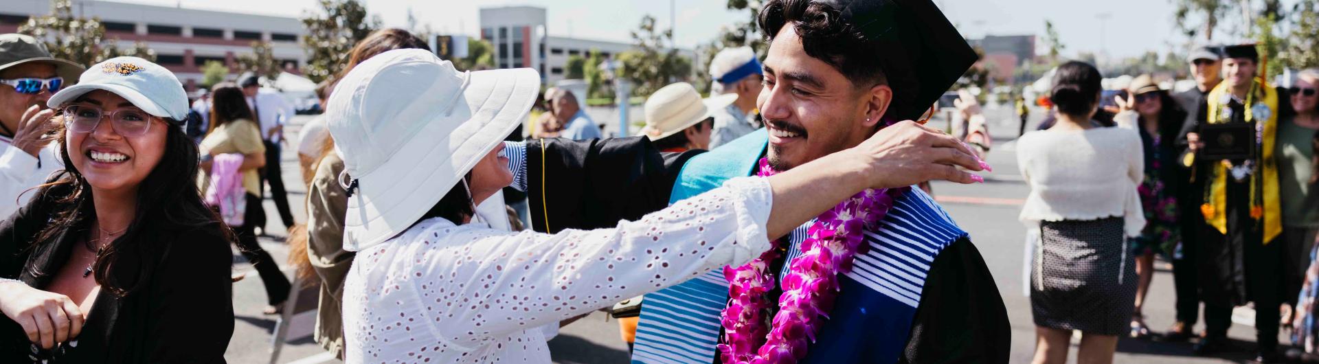 a student graduating going in for a hug with a parent