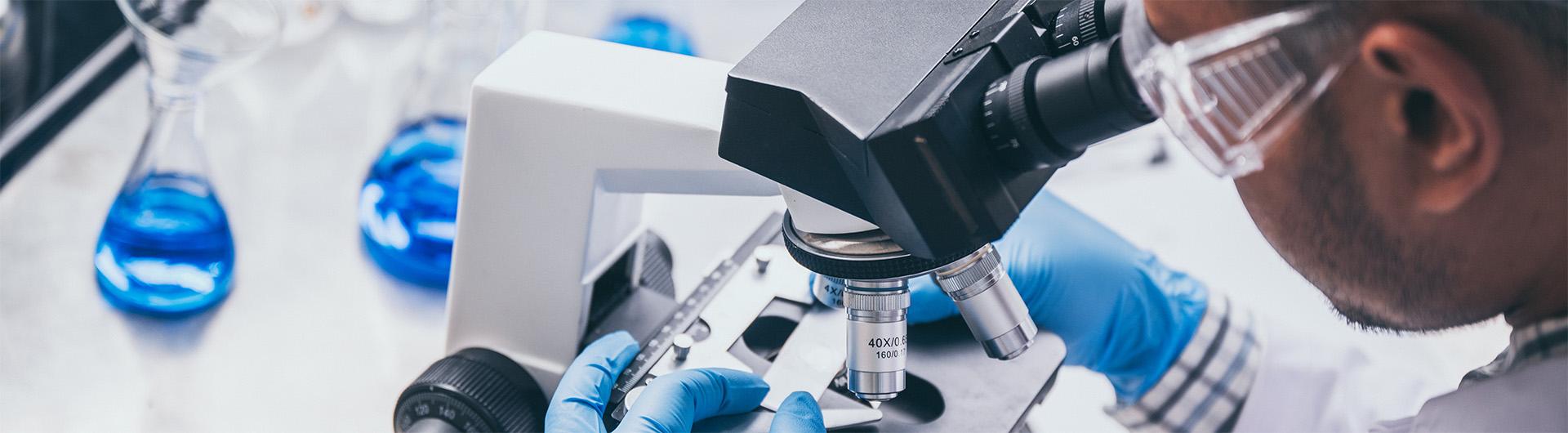 researcher looking through microscope at a slide