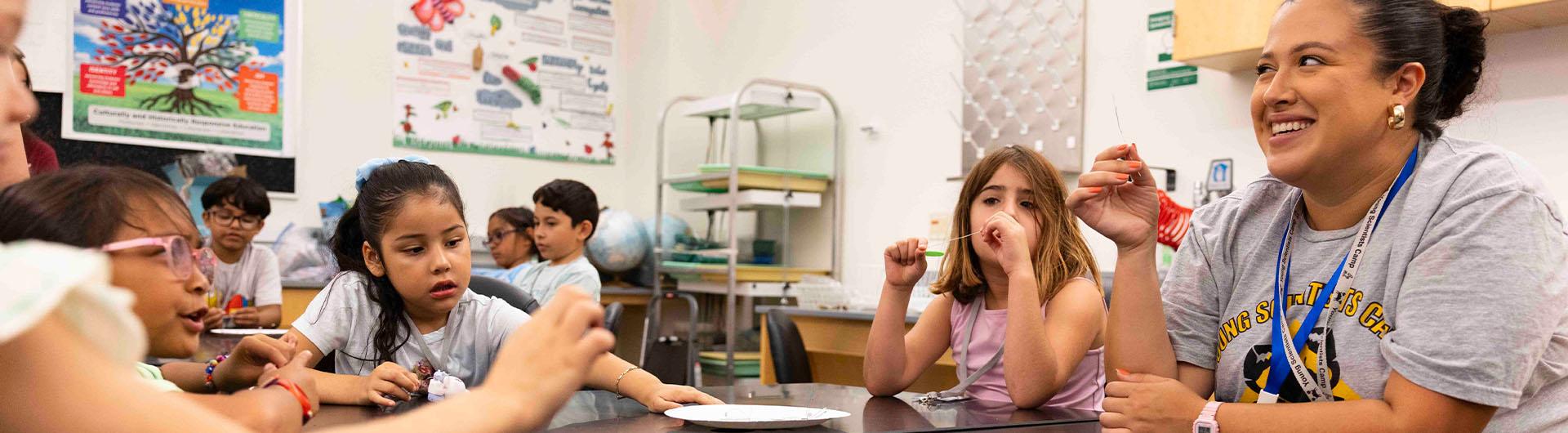 A person smiles at a table with children