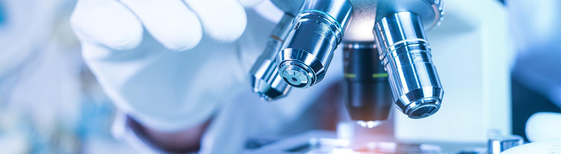gloved hand adjusting a microscope