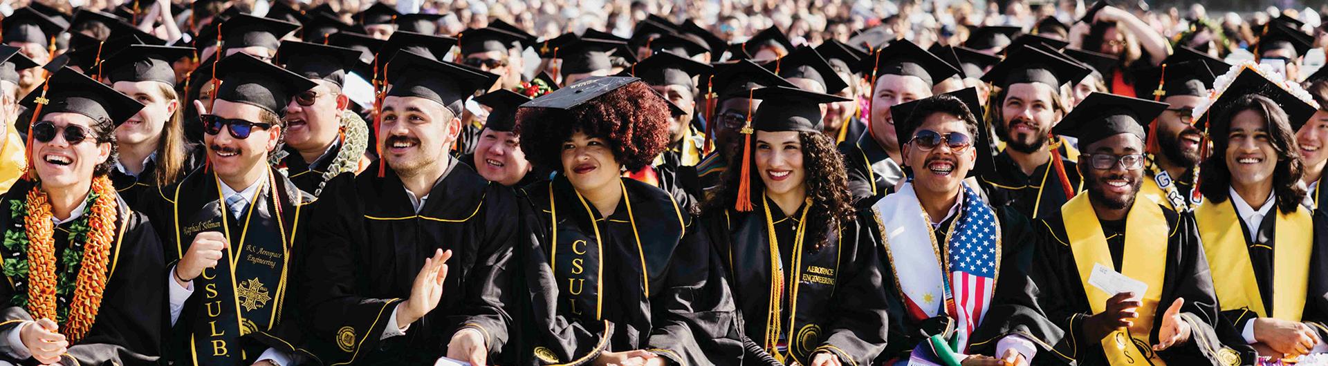 Graduates sitting at Commencement, some clapping