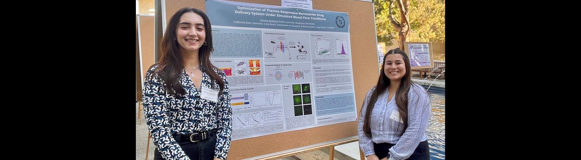 two chemistry students standing proudly in front of their poster presentation