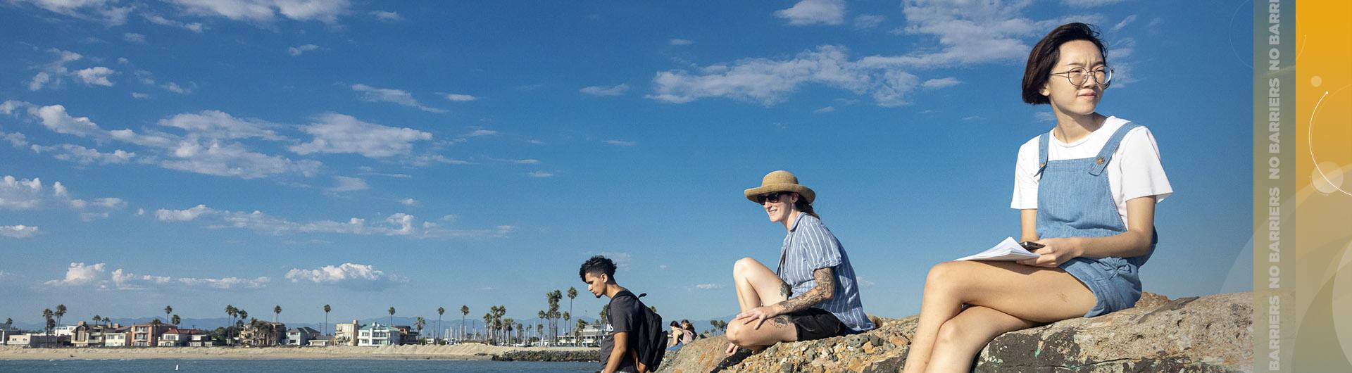 Students sitting on cliff at beach