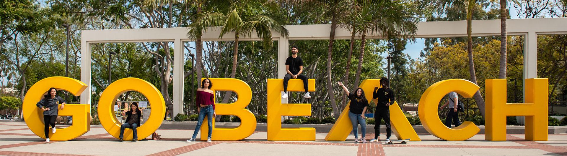 students posing next to the Go Beach sign