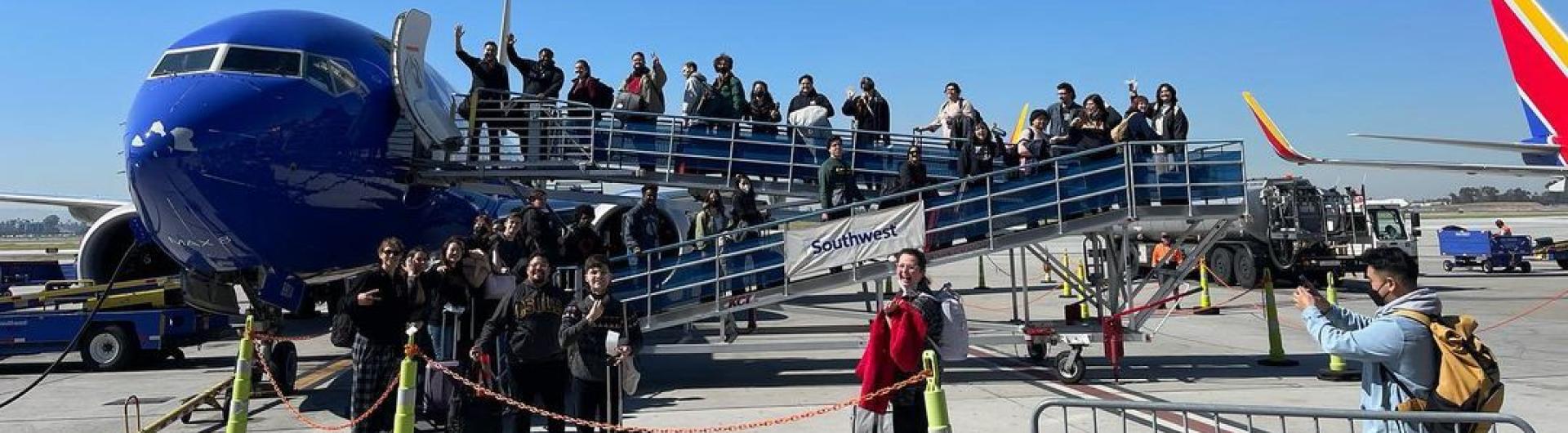 Chamber Choir Members Boarding a Plane and posing along the stairs leading to the jet door