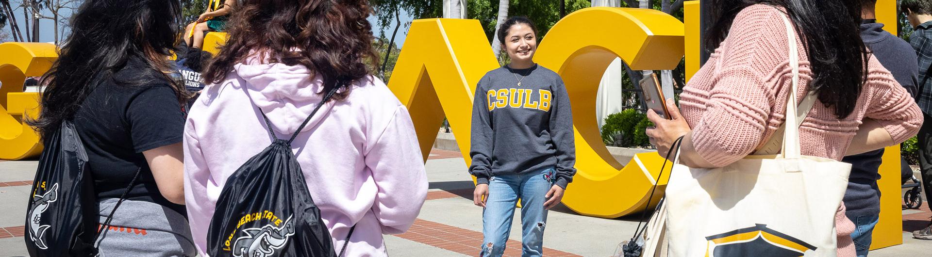 Student stands in front of BEACH sign