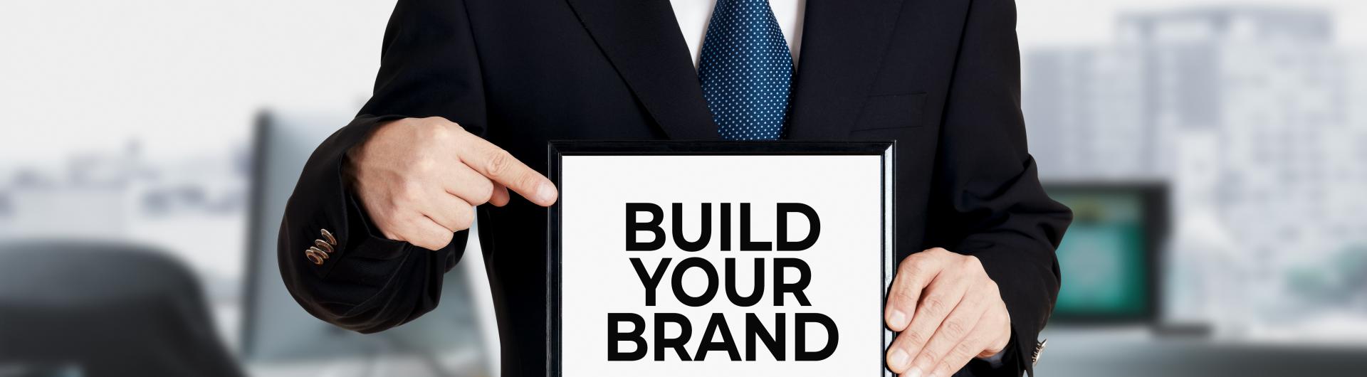 Man holding Sign saying : build your brand