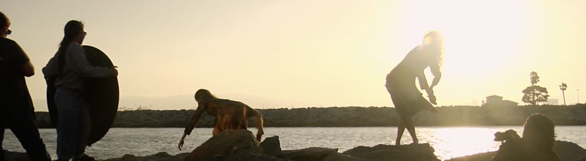 Production still from the Screendance "Aprés". Silhouette of dancers on a jetty during sunset.