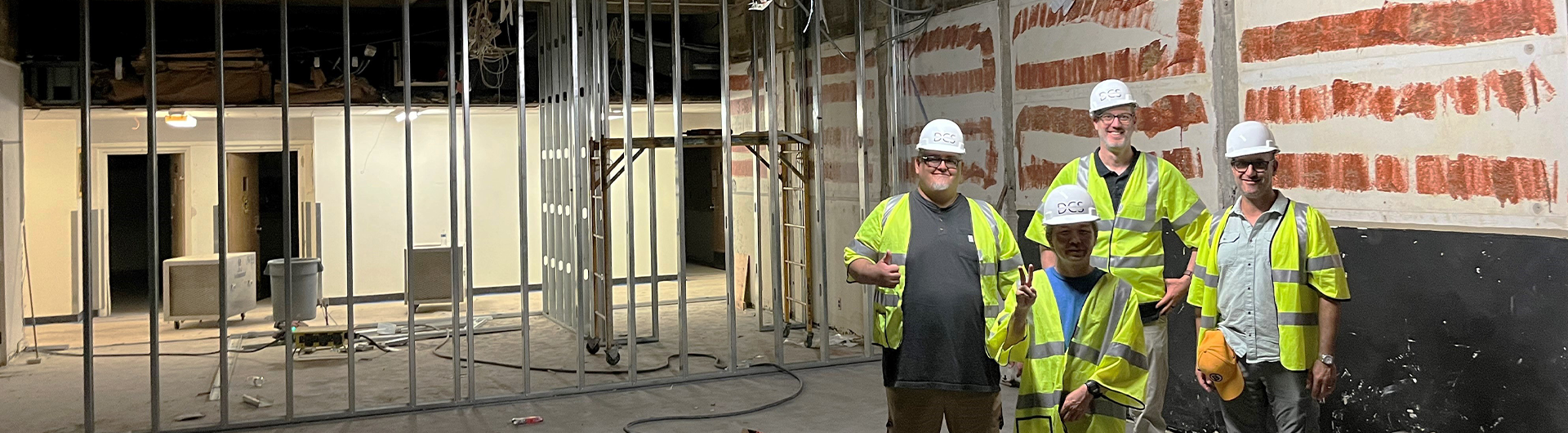 Film & Electronic Arts Staff standing with hard hats during construction of building.