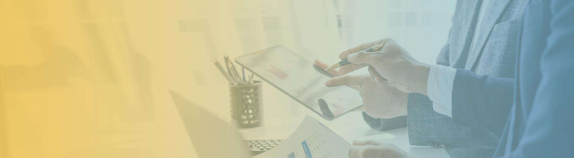 two pairs of hands sharing a tablet with graphs and data on top of a table with a pencil cup with pencils and papers