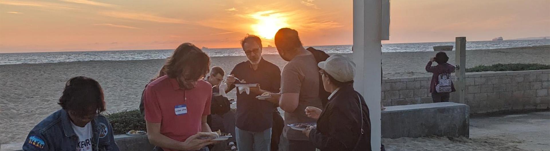 people eating dinner on the beach at sunset