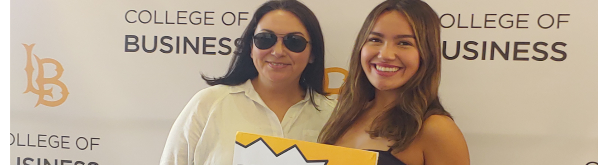 Two girls with Sign Beach Bound ant CSULB College of Business