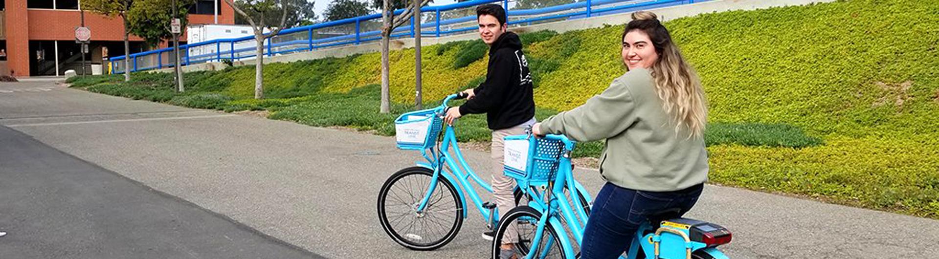 Two students riding on blue bikes