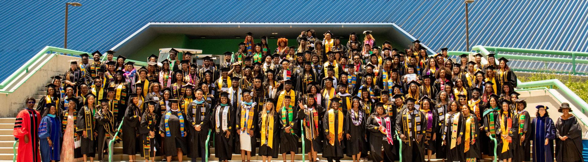 a large group of Black graduates and faculty and staff in front of the walter pyramid