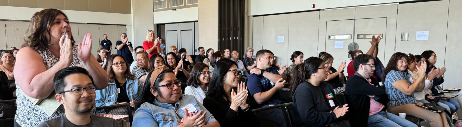 An audience claps after hearing a speech delivered.
