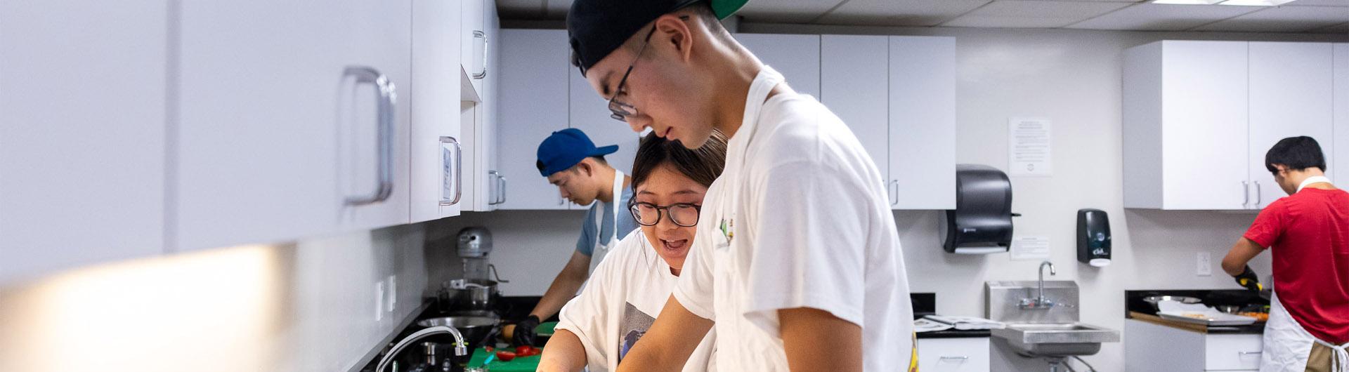 Summer LIFE students in a kitchen classroom chop vegetables and prepare food.