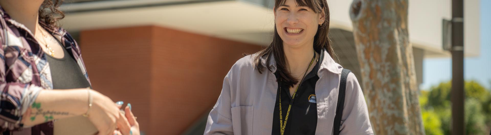 Woman smiles standing next to a large connect four game. 