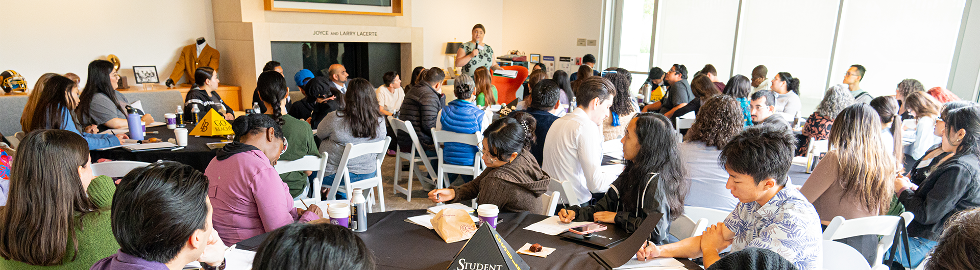 Students attending a workshop, with a speaker presenting at the front of the room