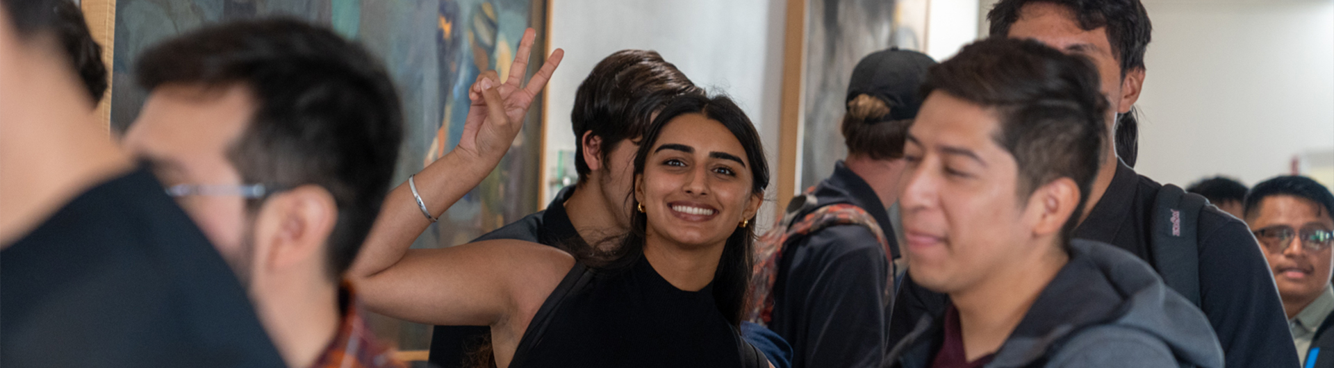 Students attending a CSULB job fair, with one student smiling and making a peace sign