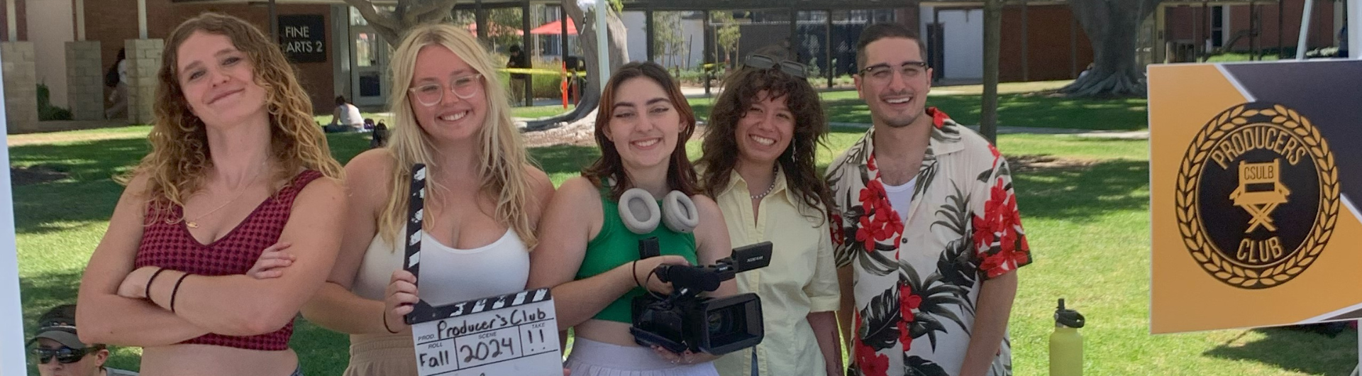 Students standing with camera, and slate under easy up at week of welcome