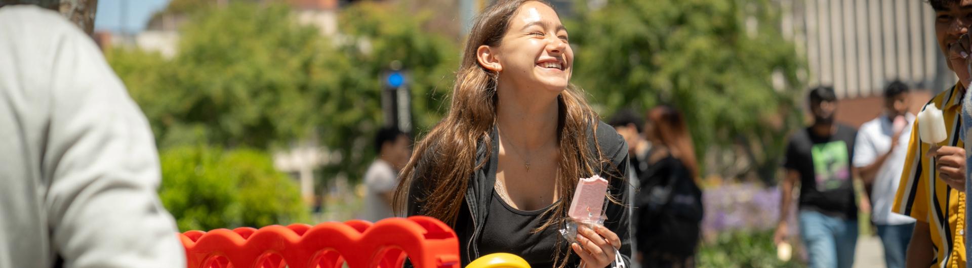 Girl laughing in front of giant Connect Four game. 