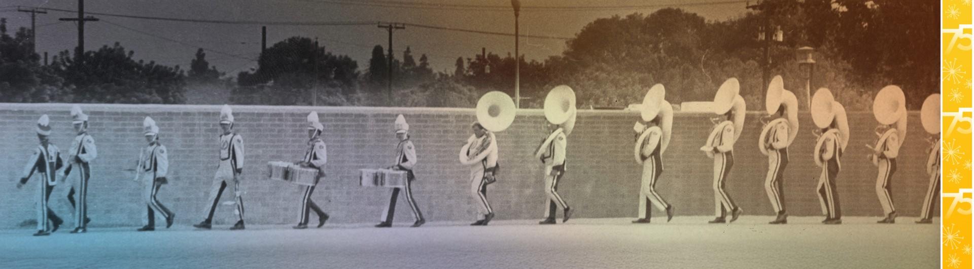 Band members marching by a brick wall
