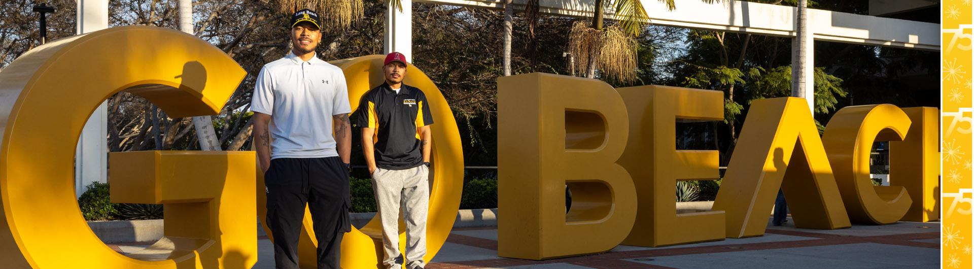 New banner image of Markel and Martel Cooper '19 in front of GO BEACH sign