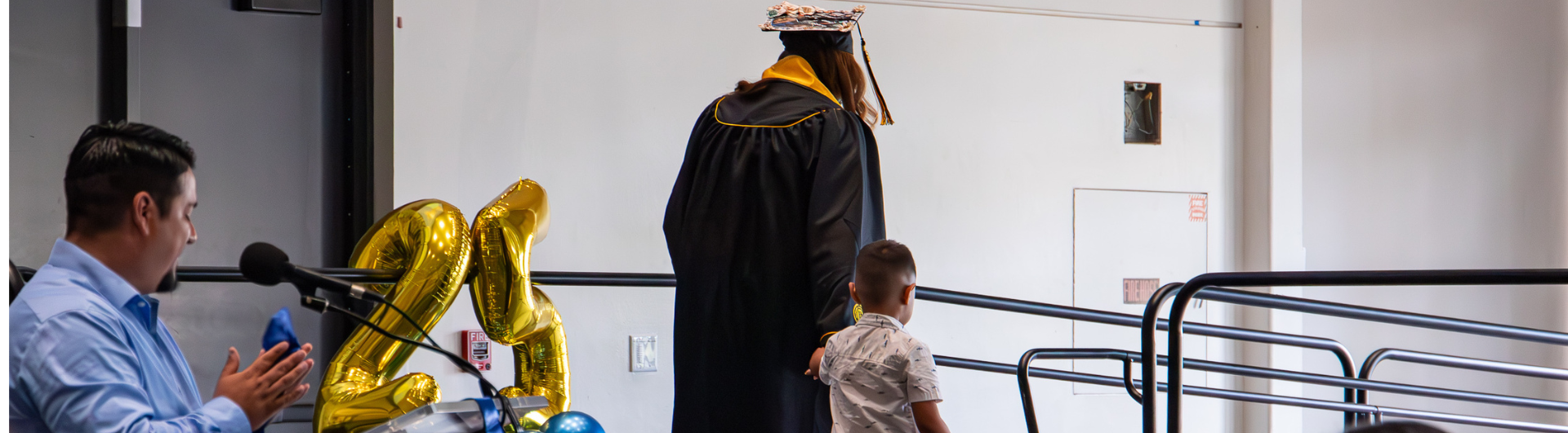 Graduate walking across stage with child                                                           