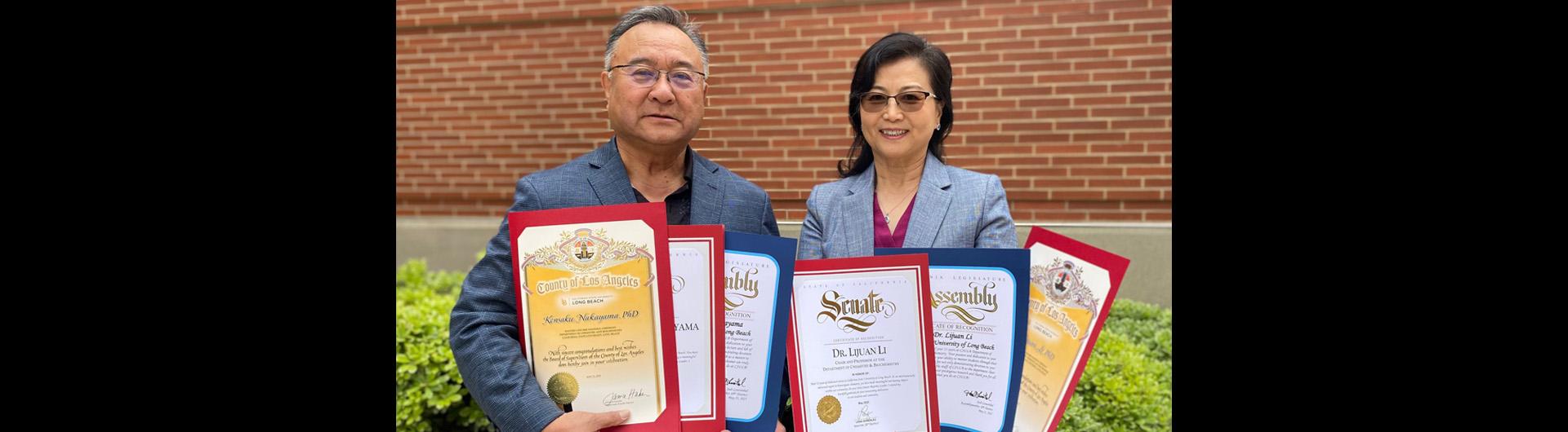 Kensaku Nakayama and Lijuan Li holding multiple award certificates
