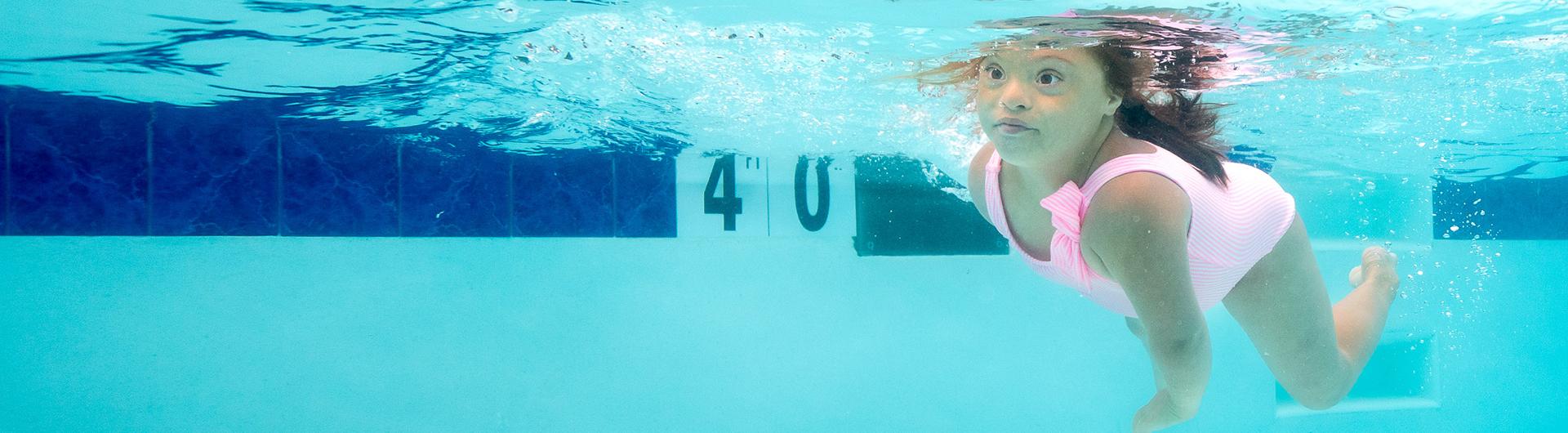 Child swims underwater near a 4-foot depth marker