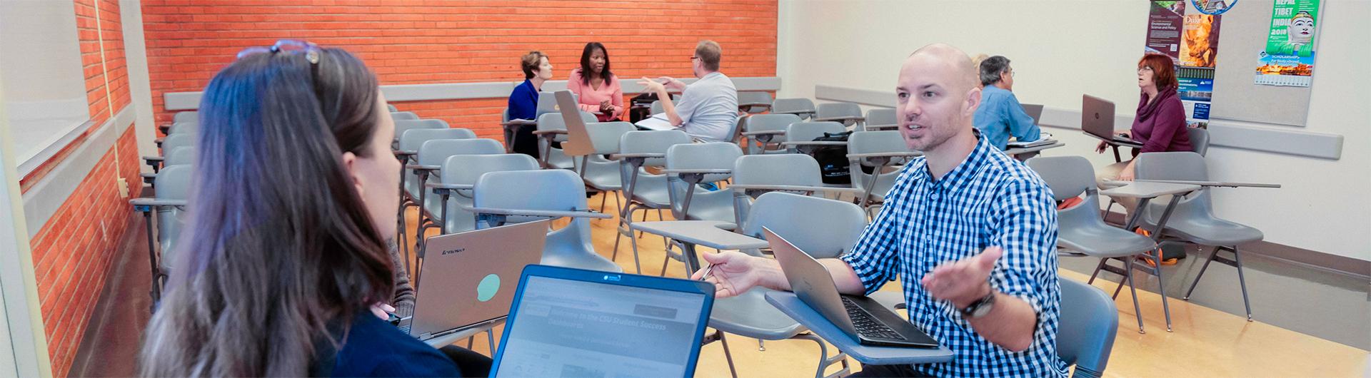 faculty talking in small groups in a classroom