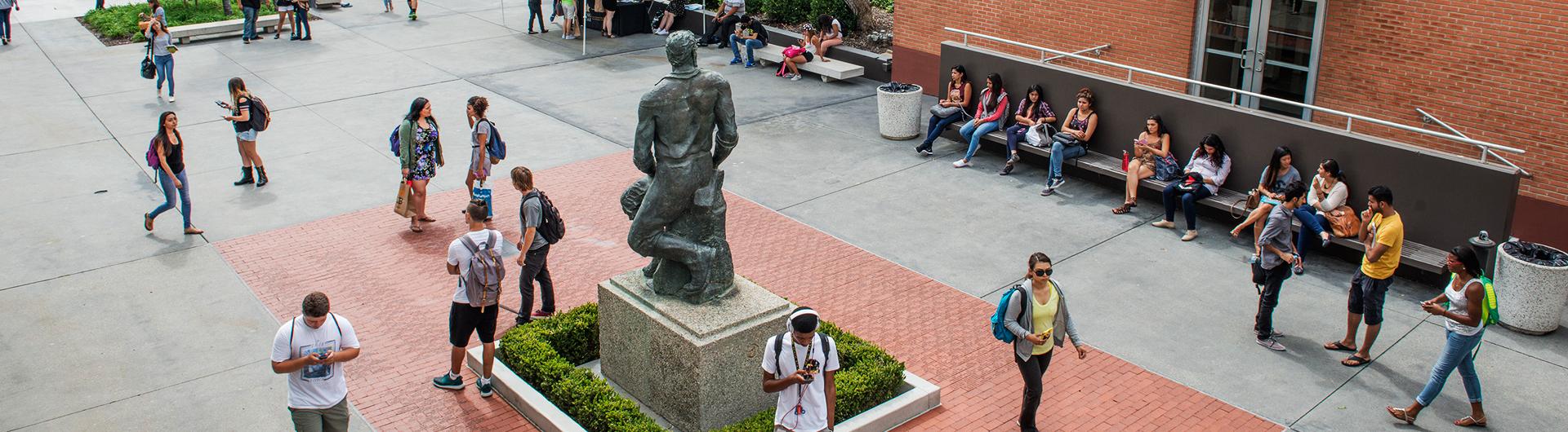 CSULB student congregate around the Prospector Pete statue on campus.