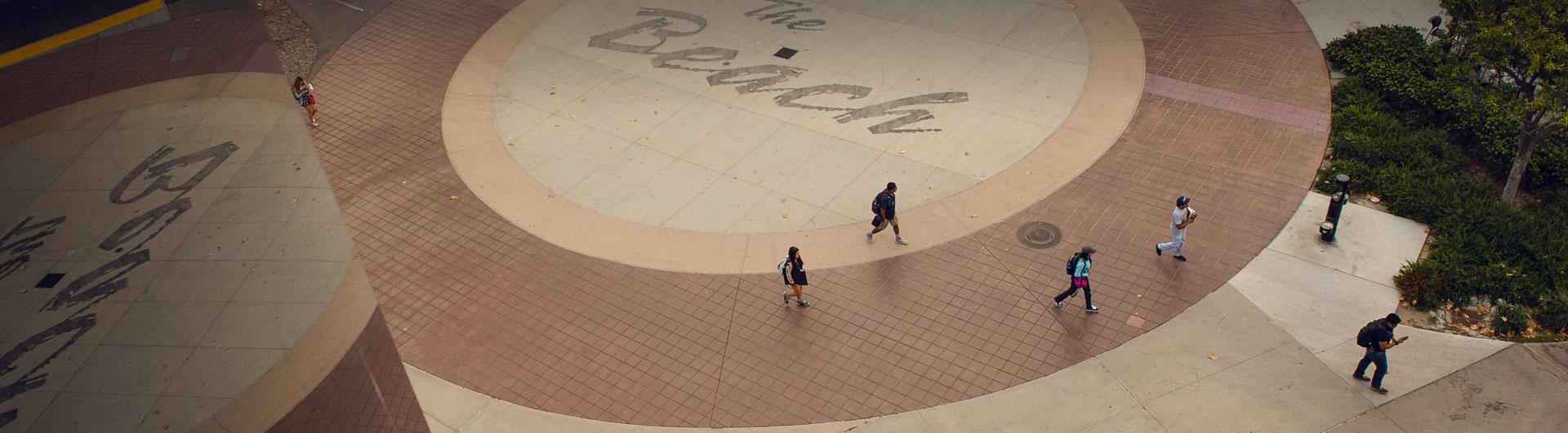 Students walking over the Beach Sign