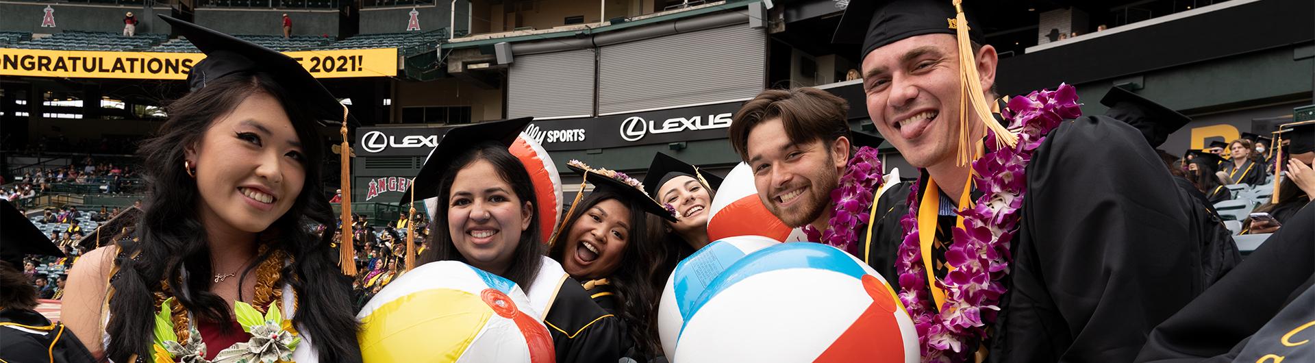 graduates holding inflatable beach balls