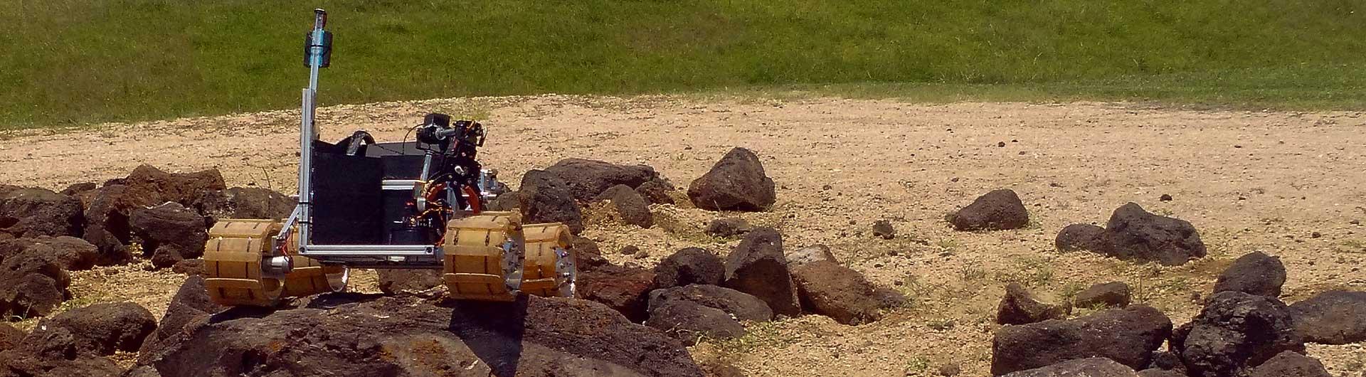 A mechanical rover navigates over some rocks