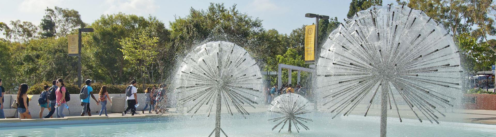 The fountains in front of CSULB's Brotman Hall as students walk by in the background.