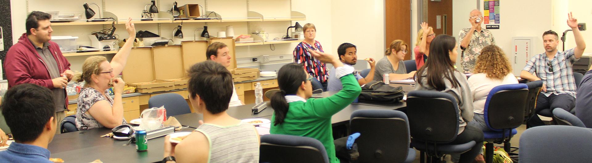 students raising hands in a classroom