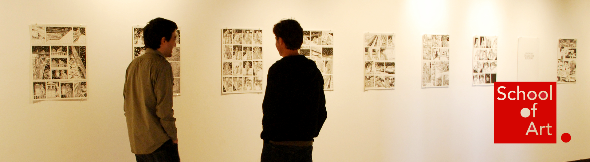 Two students looking at illustrations on a gallery wall