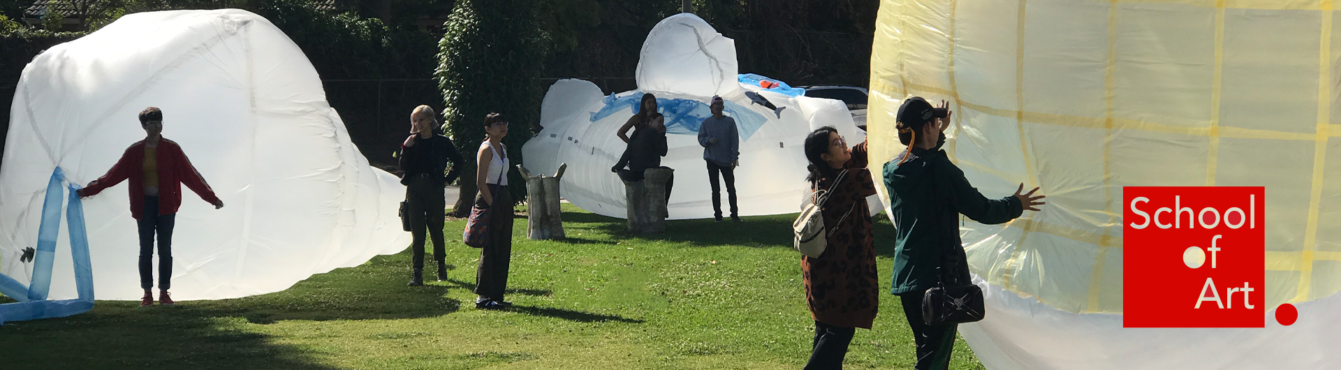 People interacting with 3D inflatable sculptures in an outdoor exhibit