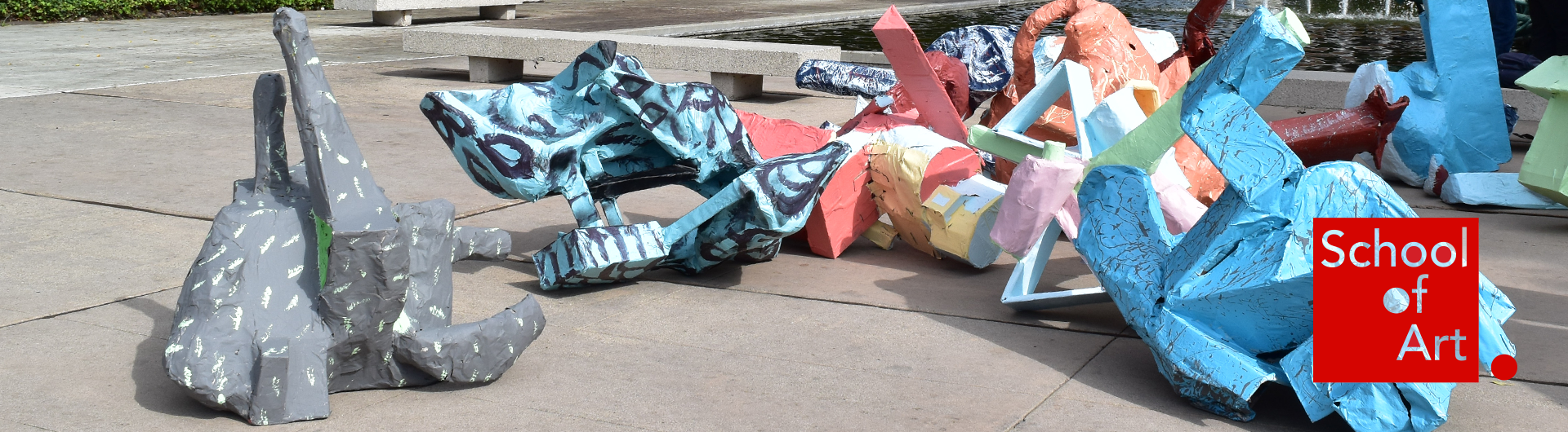 Large, colorful sculptures displayed on an outdoor concrete courtyard