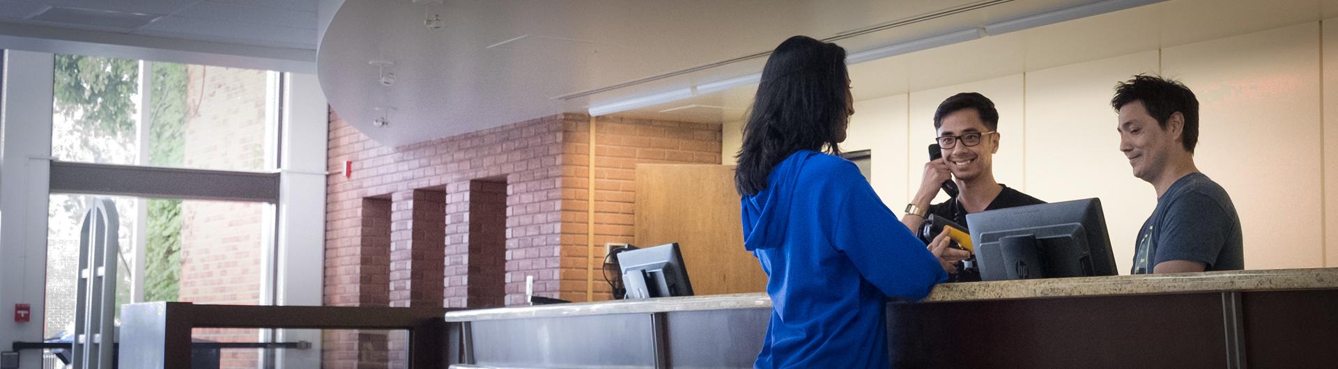 A student receives help at the University Library Circulation Desk