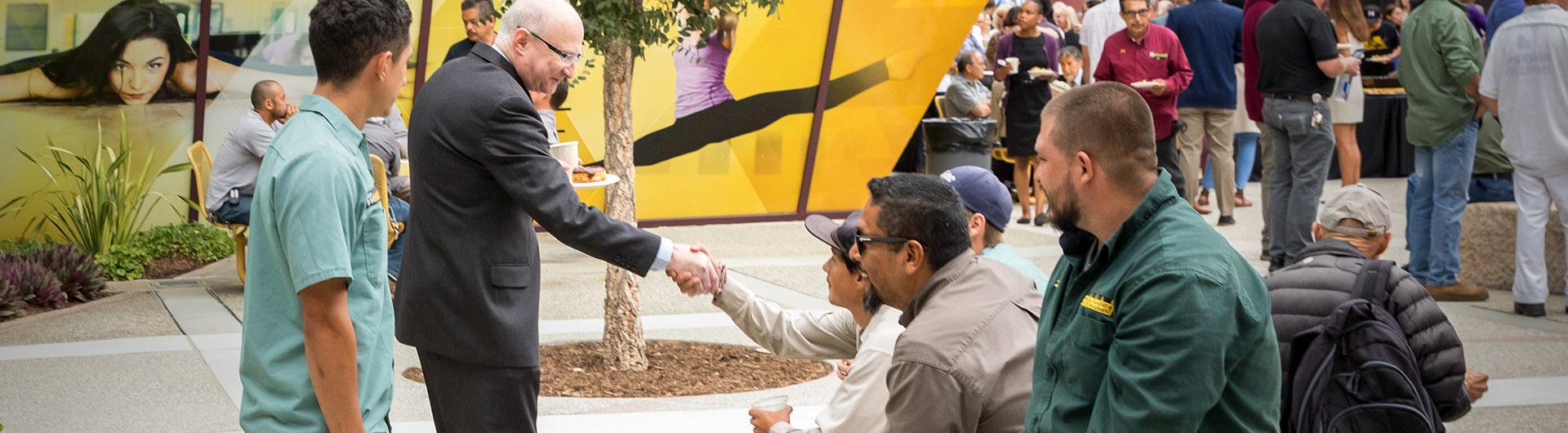 Brian Jersky shakes hands with faculty