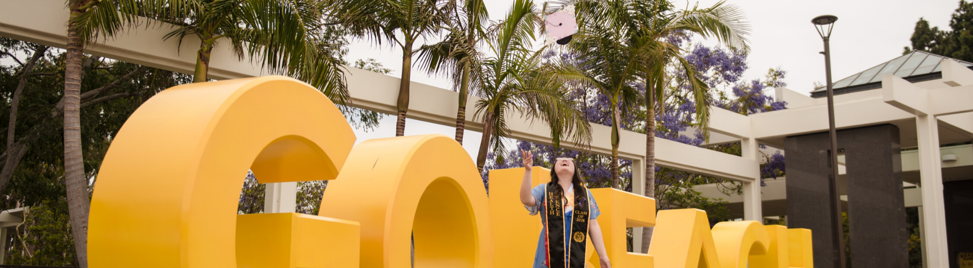 Graduate in front of Go Beach sign