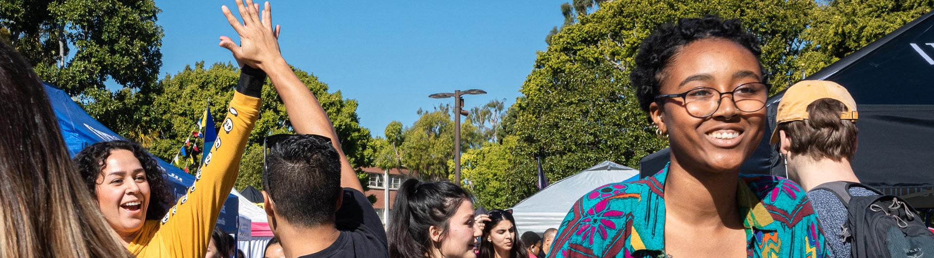 CSULB students smile and high five on campus