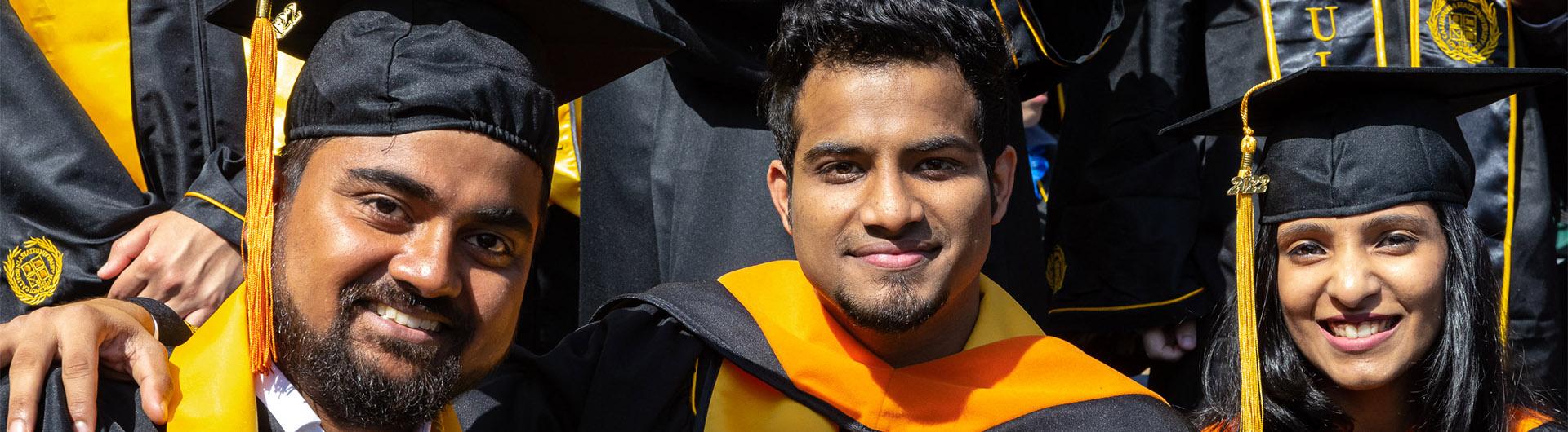 Three graduates pose at Commencement