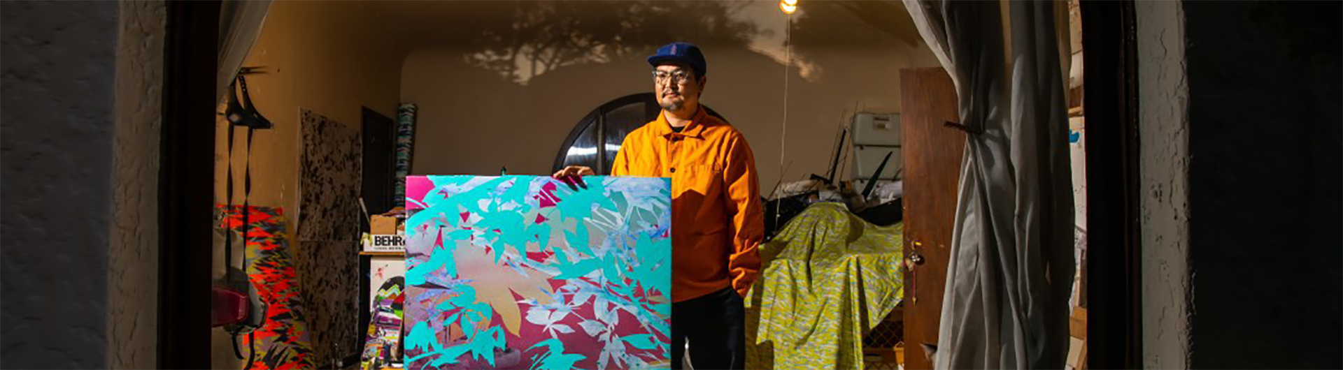 Artist Devin Tsuno standing in front of a painting