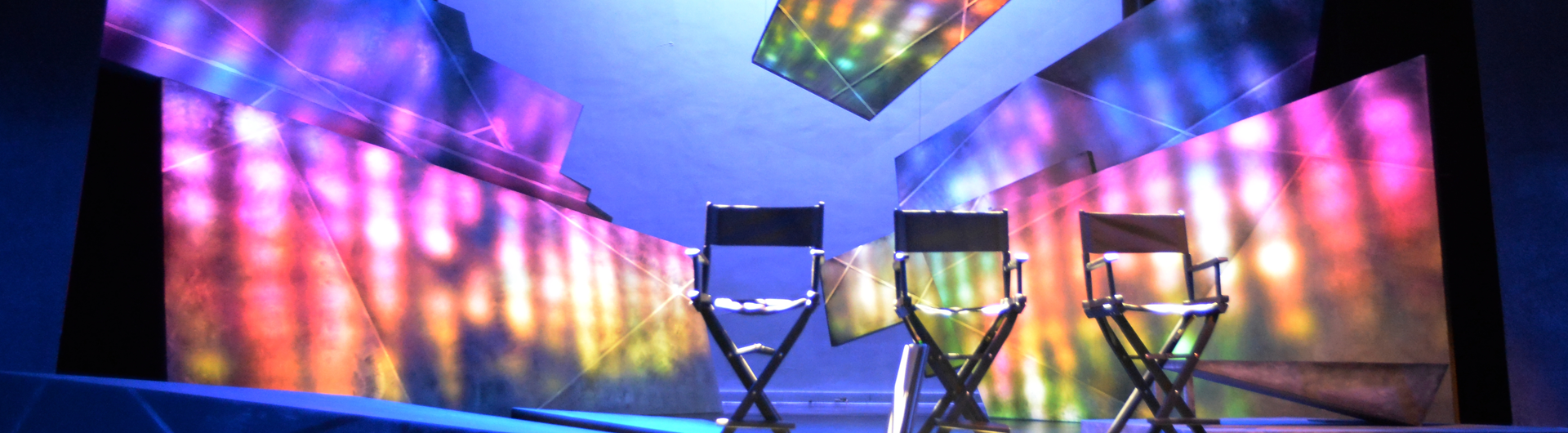 Three empty Director's chairs in front of colorful backdrop