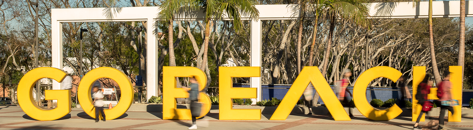 Students walking by Go Beach sign on campus